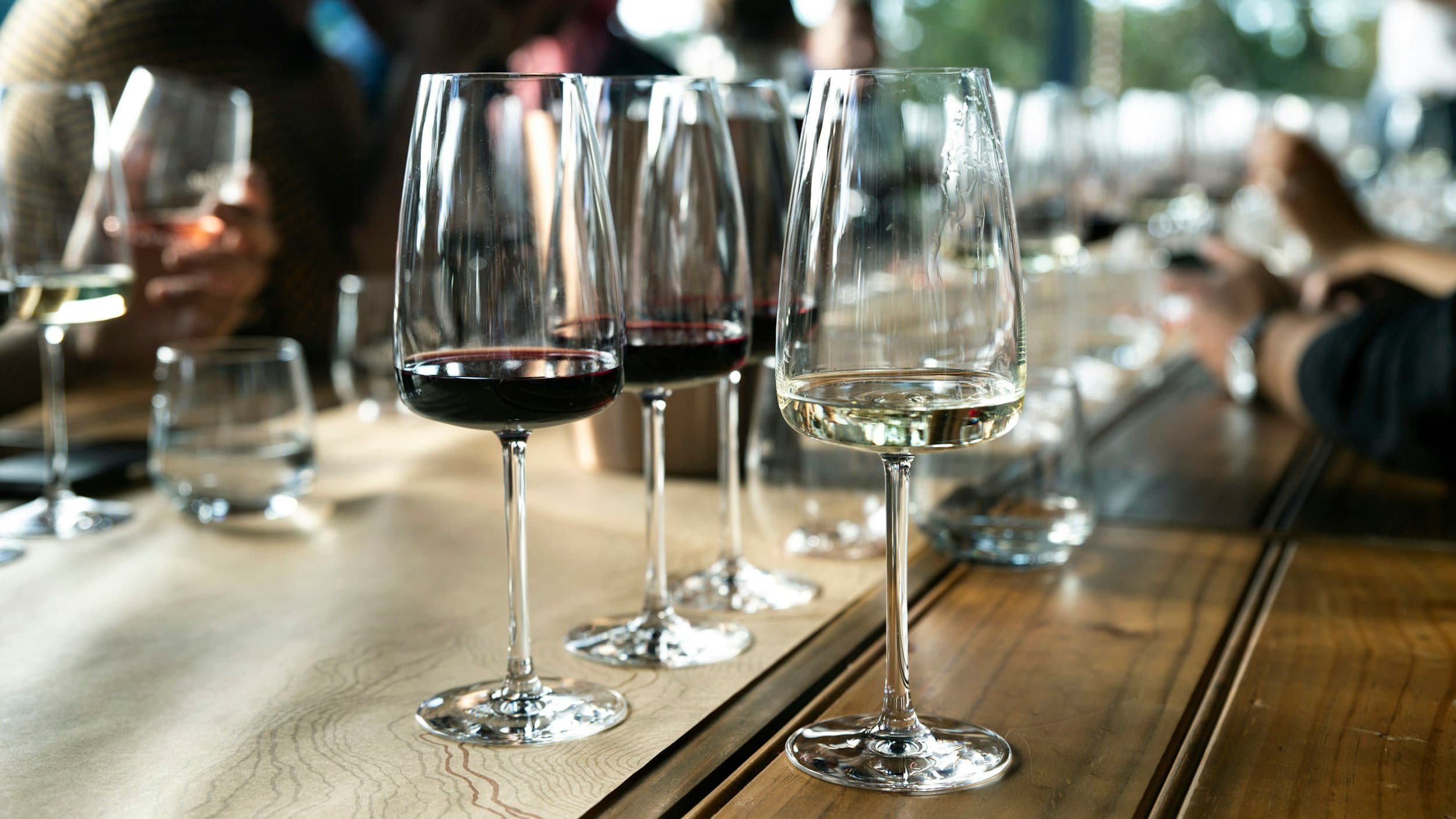 Verres de vin rouge, blanc et rosé sur une table en bois de dégustation.